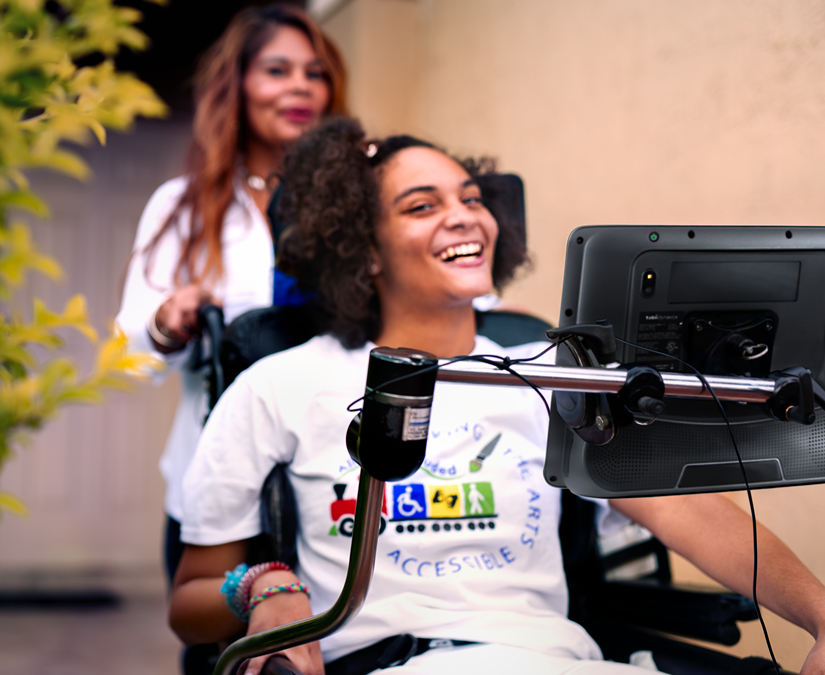 Mujer joven que usa su dispositivo de tecnología de asistencia Tobii Dynavox TD I-Series al aire libre en un parque